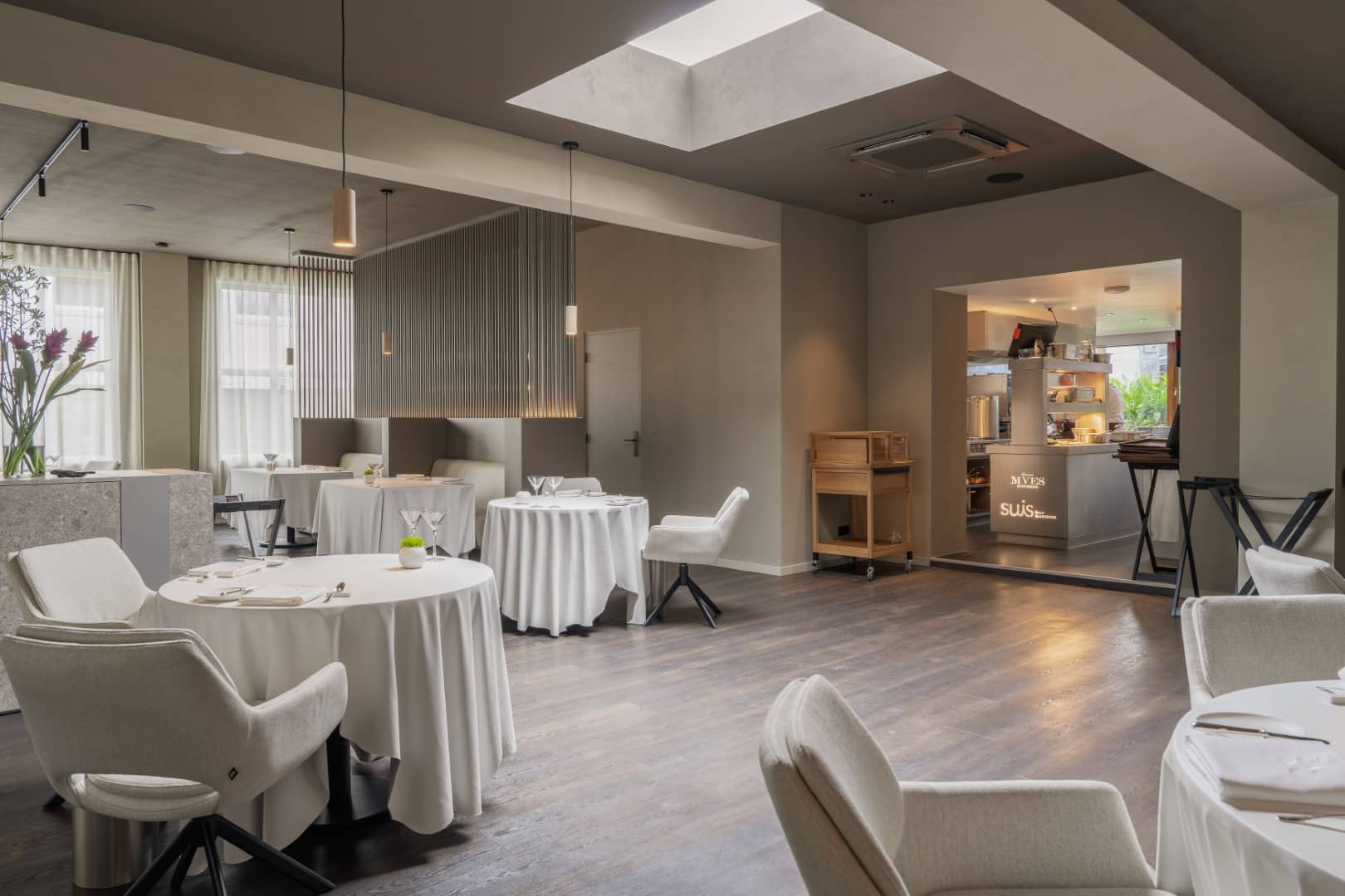 Overzicht van de fine dining ruimte met ronde tafels, lichte stoffering en warme materialen